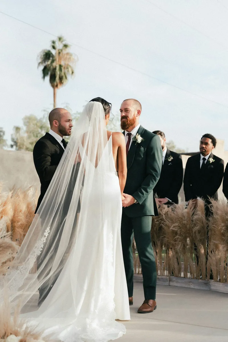 Novia y novio frente a frente durante la ceremonia, al aire libre