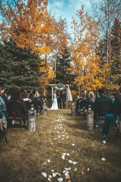 Pasillo de una ceremonia en un bosque de otoño, con invitados a los costados