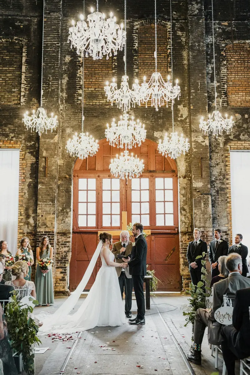 Ceremonia en un salón con arañas de luz y una puerta roja al fondo