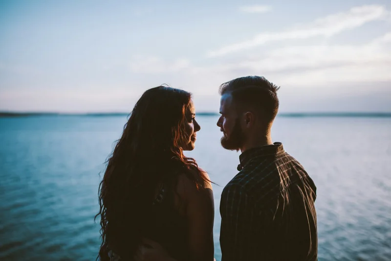 Pareja mirándose frente a un lago
