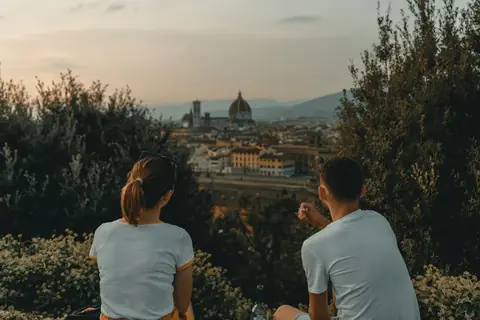 Pareja sentada de espaldas mirando una ciudad desde un mirador