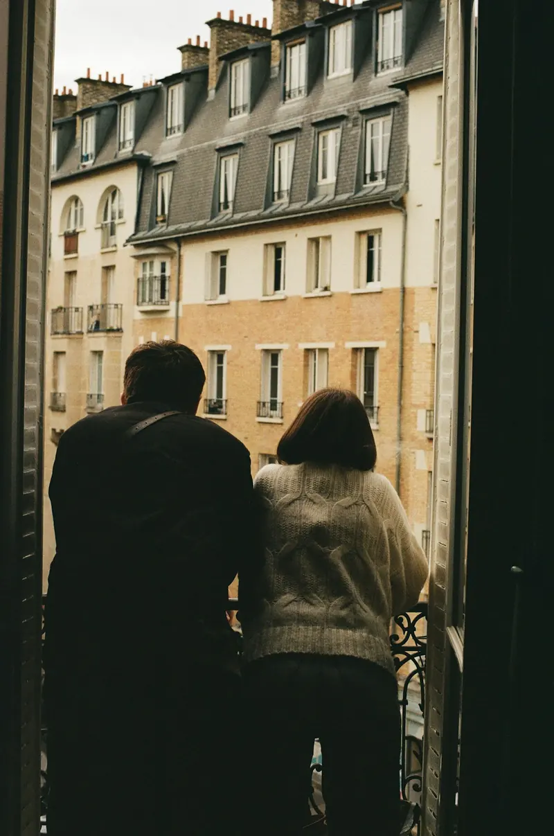 Pareja abrazada en una ventana que da a la calle