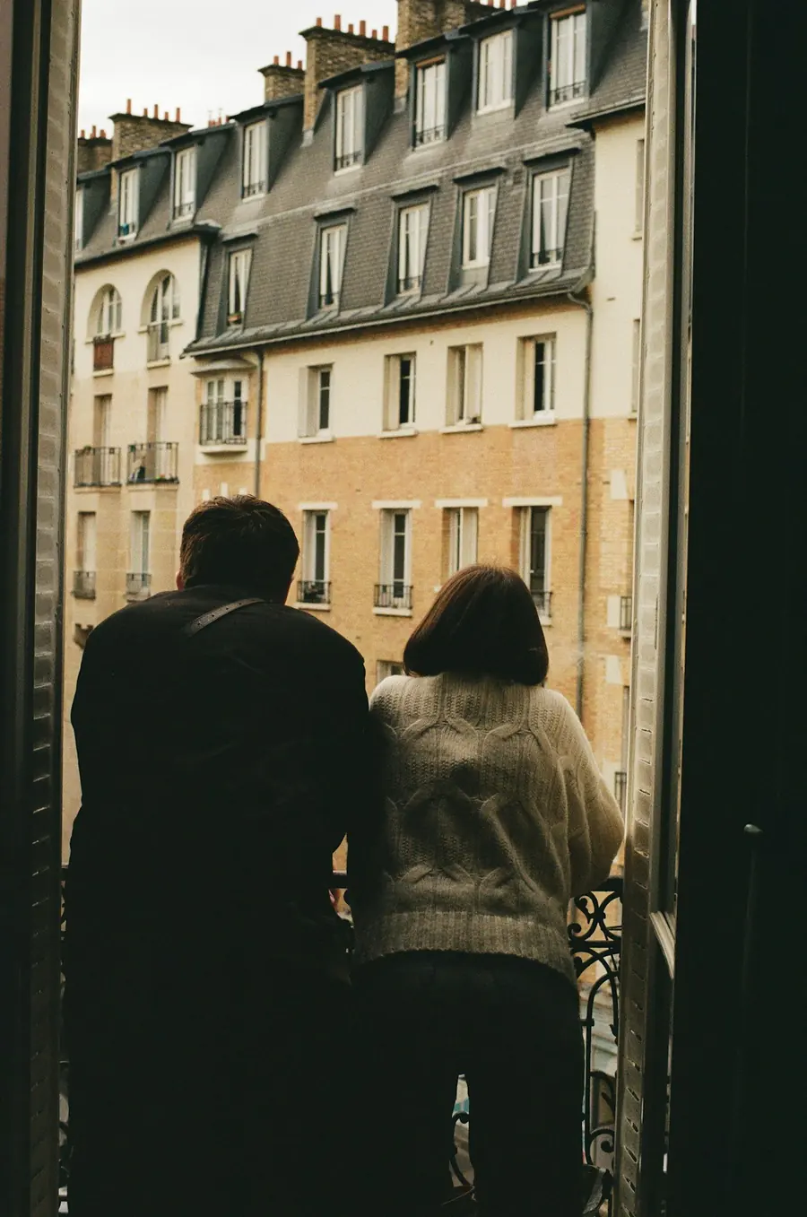 Pareja abrazada en una ventana que da a la calle