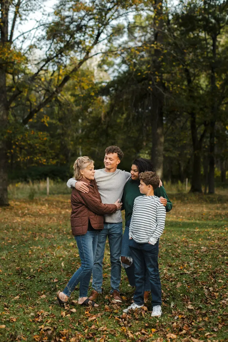 Familia de cinco abrazada en un parque con hojas de otoño