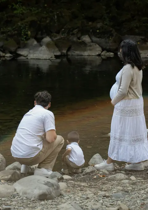 Familia junto a un río, el padre agachado con un niño