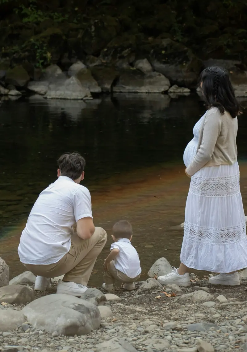 Familia junto a un río, el padre agachado con un niño
