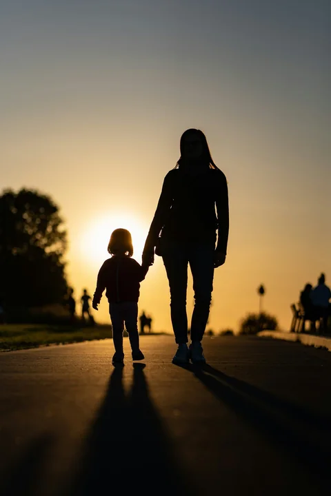 Silueta de una madre y su hija caminando hacia el sol