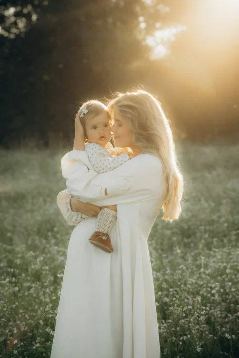 Madre con su hija en brazos en un campo con flores